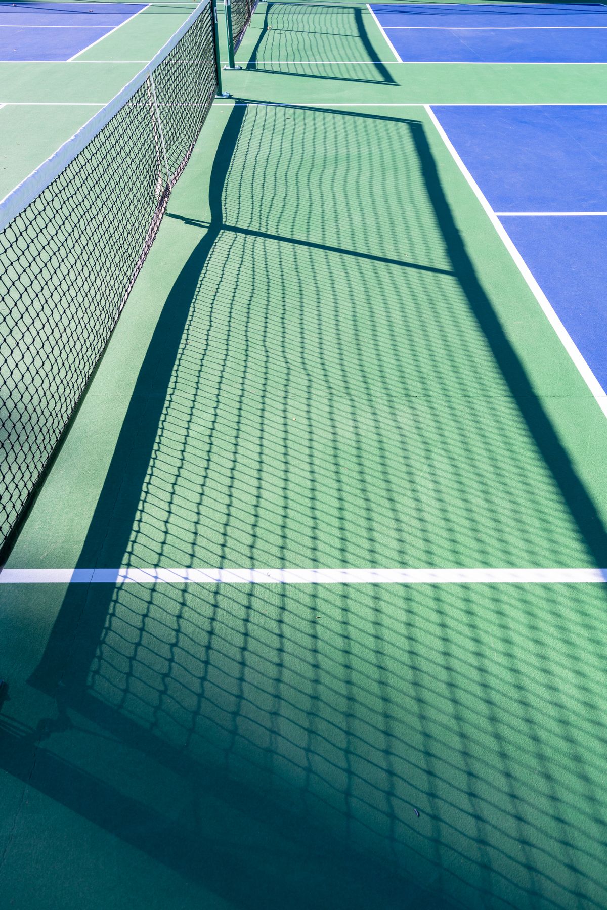 Zonovergoten pickleball-baan met schaduw van het net
